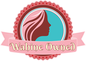 A circular emblem featuring a stylized female silhouette with flowing hair inside a teal and red round frame, surrounded by a pink ribbon. The text "Wahine Owned" is displayed on the ribbon at the bottom. The background and theme colors are pink and vibrant, evoking the spirit of a Maui bakery.
